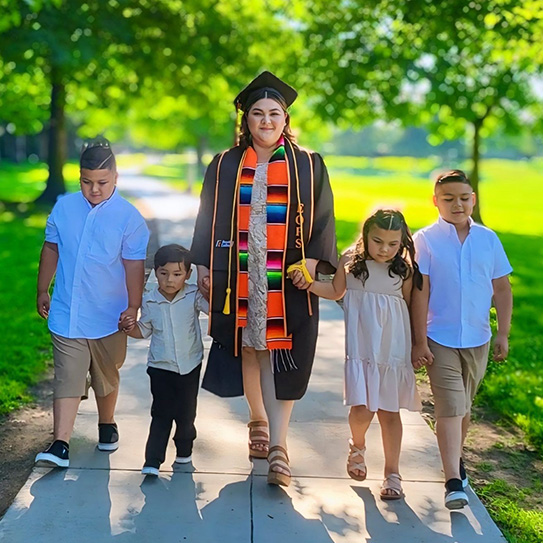 Franny Lara in graduation regalia walking with her family.
