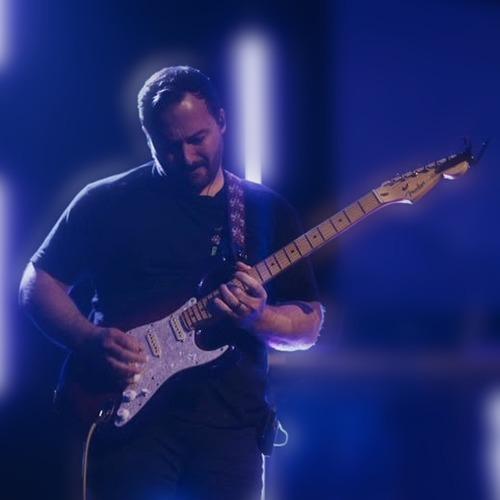 Austin Cantrell plays an electric guitar onstage under blue and purple lights.