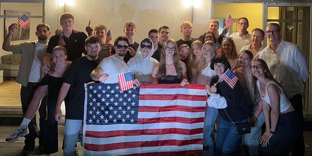Group photo of athletes smiling while holding an American flag