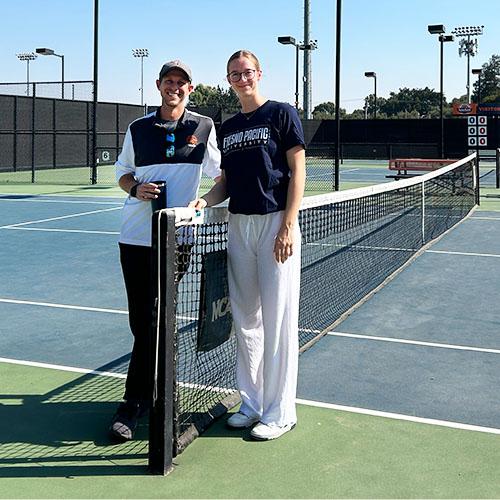 Photo of a coach and student standing on tennis court