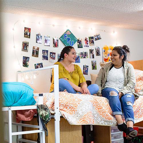 FPU students sitting on a bed in a dorm room