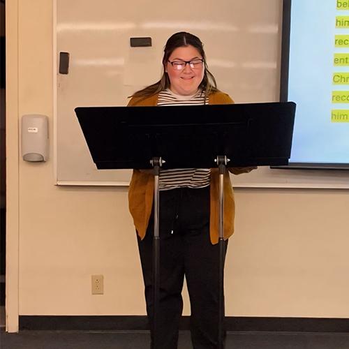 Franny stands behind a podium in a class at FPU.