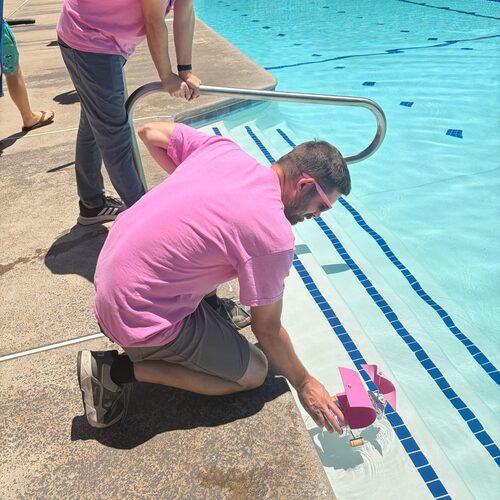 Two FPU community members prepare to place a small handmade boat into the campus pool.