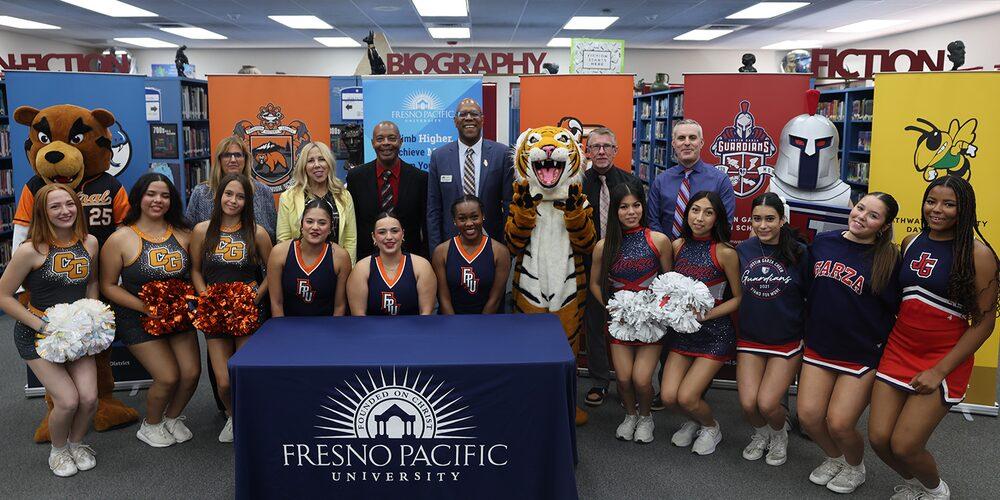 Fresno Pacific University and local school representatives pose with cheerleaders and mascots during an MOU signing ceremony.