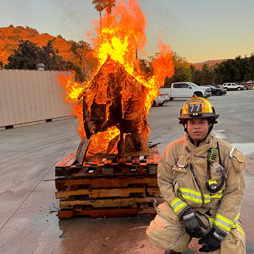 AJ Kirby squatting by a fire demonstration