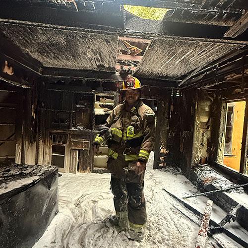 AJ Kirby standing in a fire-demolished building