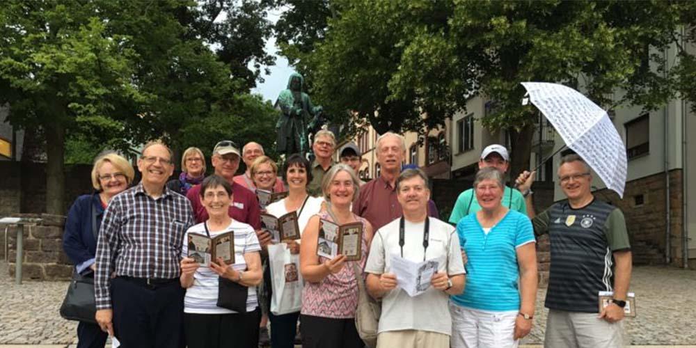 Group photo of travelers smiling with the statue of Bach behind them
