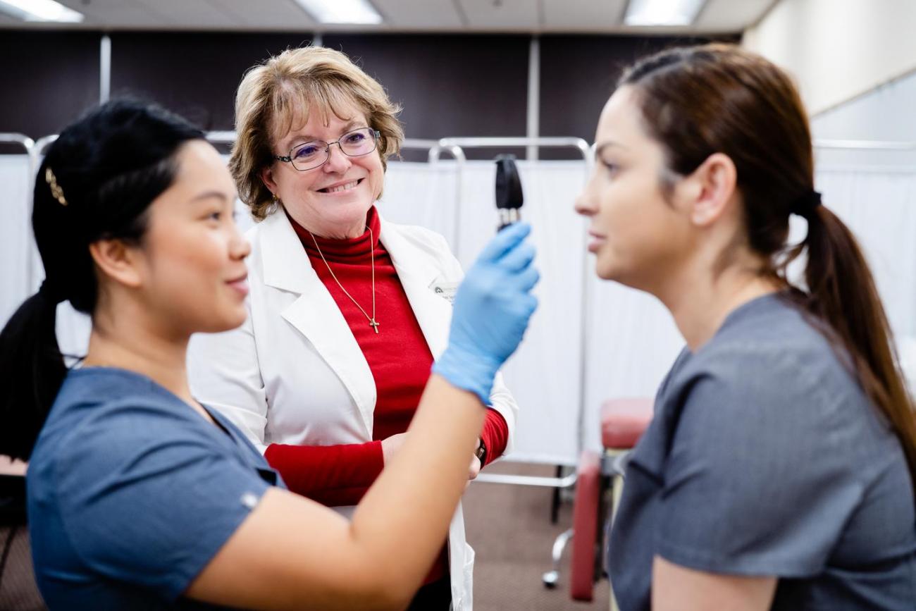 A nursing student demonstrating an eye examination