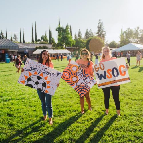 Three students holding hand made signs