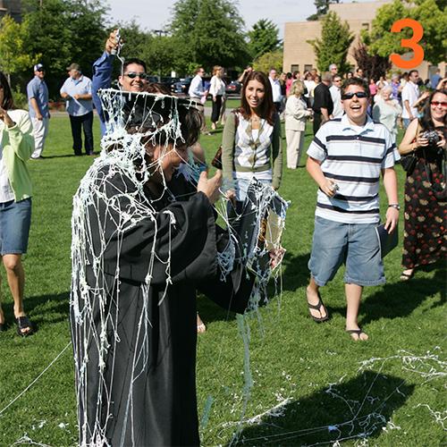 Photo of a student in graduation robe covered in silly string.