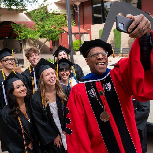 President Stephens taking a selfie with students at grad