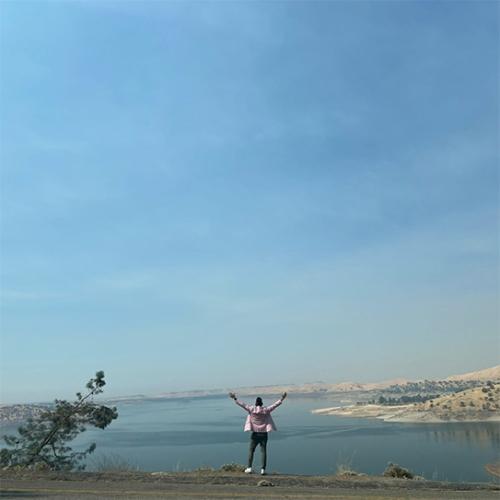 Image of figure lifting hands with a landscape in the background