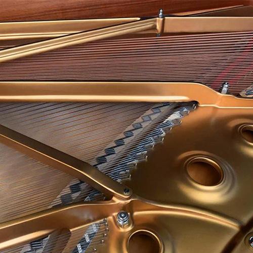 Close-up photo of a grand piano's interior showcasing strings and the gold frame.