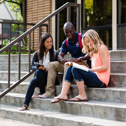 Image of students sitting on stair steps reading and smiling