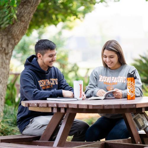Students outside sitting at a table smiling