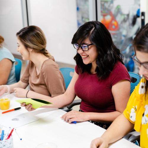 Students sitting at a table, in a row, working