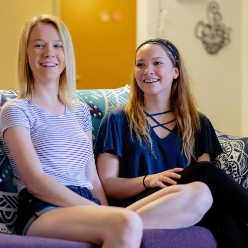 Two students sitting on a couch in a common area