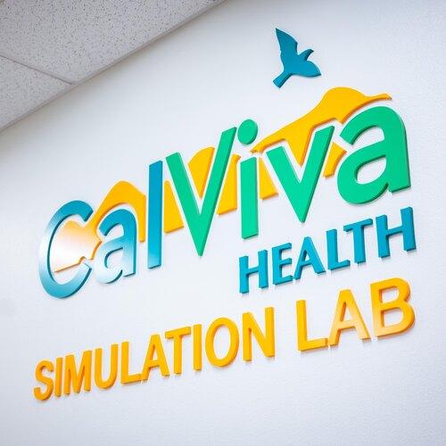 Colorful CalViva Health Simulation Lab sign mounted on a white wall.