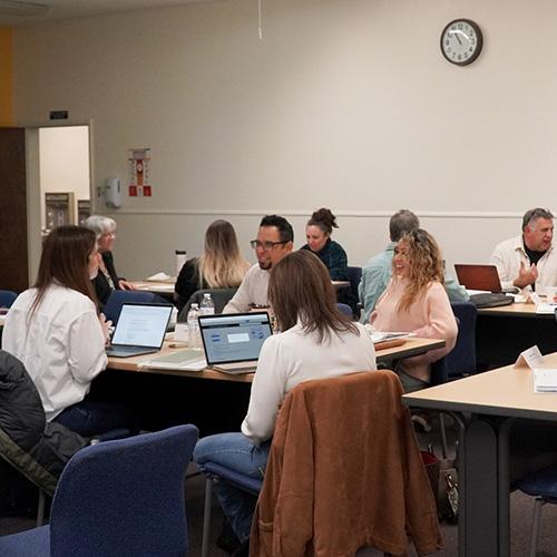 A group of people with laptops sitting at a workshop.