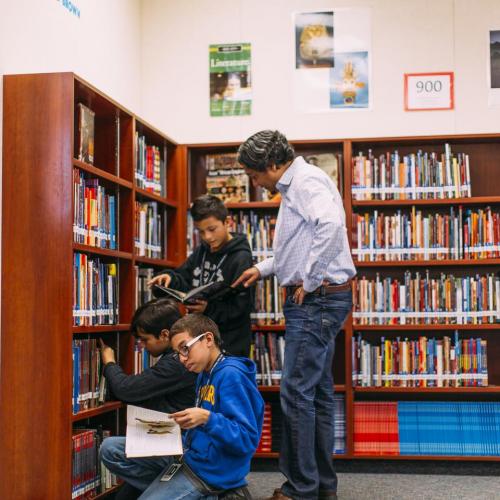A grade school teacher with students in a library