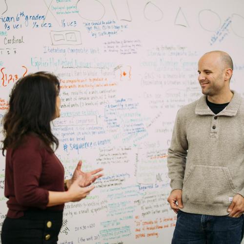 Two instructors having a discussion in front of a whiteboard
