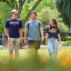 Three FPU students smile as they walk together across campus.