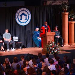 Fresno Pacific University President André Stephens speaks at the podium during Convocation 2026 as faculty and students look on.
