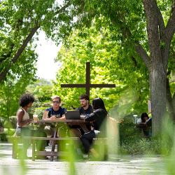 FPU students sitting around a table with a wooden cross behind them