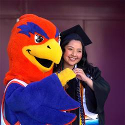 Sunny the Sunbird standing next to FPU graduate