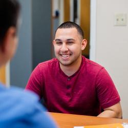 Smiling Fresno Pacific University student meets with an adviser across a table.