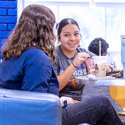 Two students sitting at a table and having a conversation