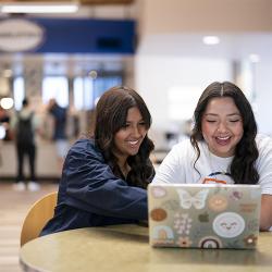 Two students sitting at a table and smiling