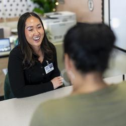 A woman sits behind a desk helping someone