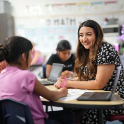 Teacher sitting in a classroom helping a student