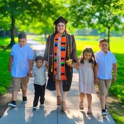 Franny Lara in graduation regalia walking with her family.